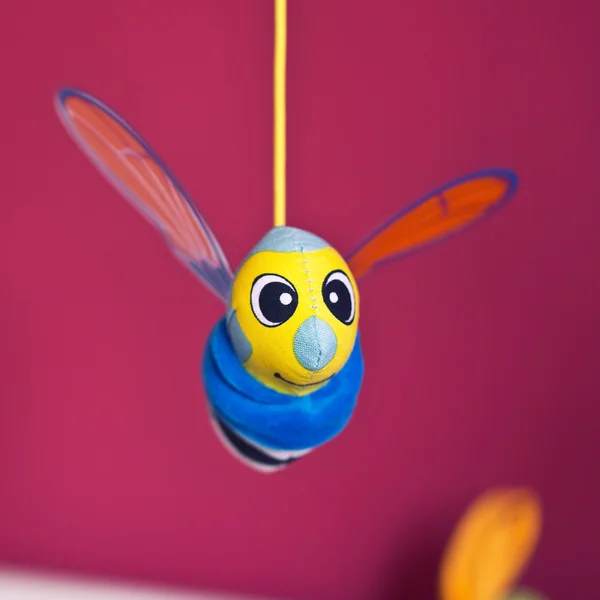 Little bee hanging above baby bed — Stock Photo, Image