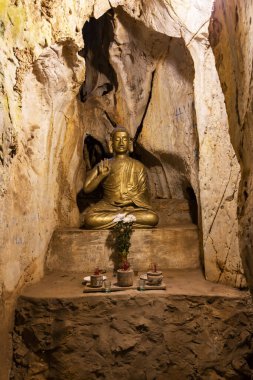 Marble Dağları 'ndaki bir kireçtaşı mağarasında parlayan bir Budist heykeli ve sunağı olan Grotto Tapınağı, Da Nang, Vietnam