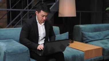 Asyalı iş adamı dizüstü bilgisayarla çalışıyor. Etnik işadamı dizüstü bilgisayara bakarak konuşuyor, online konferans ofis sohbeti video konferans konsepti. Giyin. Çevrimiçi seminer.
