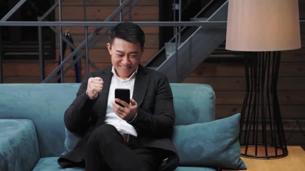 Zaskoczony podekscytowany azjatycki mężczyzna Zwycięzca staje się czytać dobry internet Aktualności Amazed Man by successfully Deal at work. Koncepcja: Sukces, Startup Business, Praca online. Sukces w kryzysie. Technologia IT. — Wideo stockowe