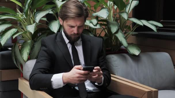 Hombre de negocios navegando por teléfono en la sala de eventos comunicarse con el equipo durante coronavirus hombre barbudo feliz navegando por Internet, Redes Sociales, Citas Aplicaciones tocando mensaje de desplazamiento reunión de correo electrónico. — Vídeos de Stock