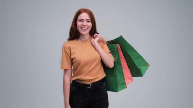 Mutlu Kafkasyalı kızıl kadın renkli alışveriş torbalarını gösteriyor..