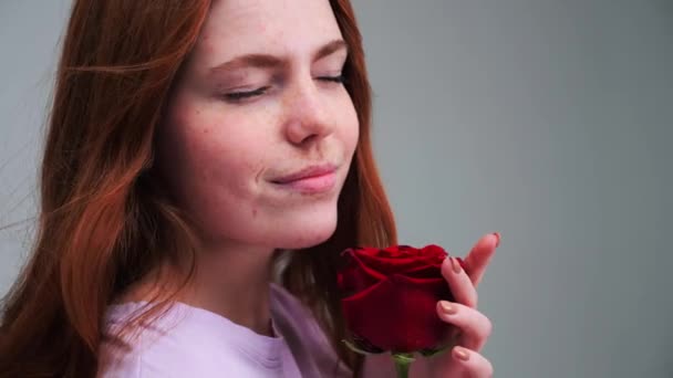Rudowłosa dziewczyna z różą pozująca w studio. Emocje ludzi. — Wideo stockowe