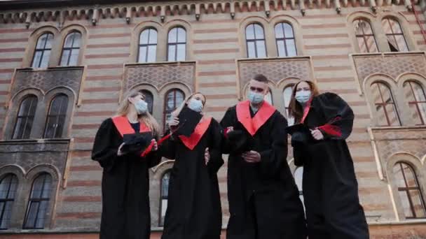 Groepsstudenten gegooid dansen knuffelen tijdens het vieren van afstuderen dag covid19. — Stockvideo