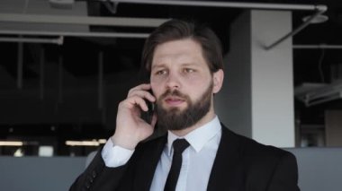 Klasik takım elbiseli bir iş adamı modern ofis binasında iş arkadaşlarıyla telefonda konuşuyor neşeli bir adam iş yerinde telefon görüşmesi yapıyor. Sosyal ağ. İnsanlar.