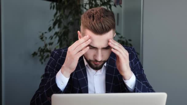 筋肉の緊張に苦しむひげを生やしたビジネスマンは、コンピュータの過労や鎮静剤の仕事のライフスタイルのために痛みを伴う頭の感情を持っています。疲れている従業員はオフィスでの仕事に圧倒される — ストック動画