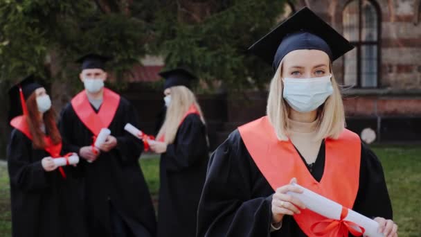 Porträt einer schönen blonden Absolventin in medizinischer Maske während eines Covid19. — Stockvideo