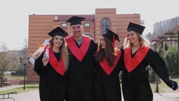 Los graduados de la Academia en batas y certificados van a celebrar la graduación. — Vídeo de stock