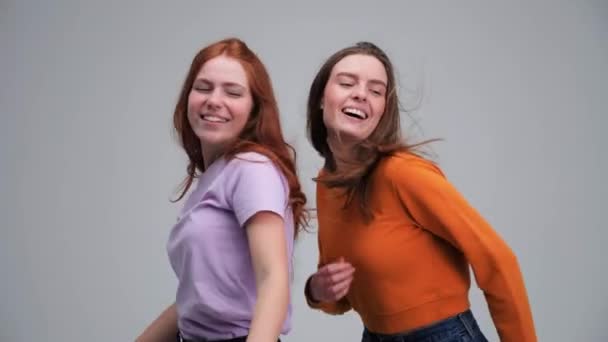 To jenter i 20-åra danser isolert i et gråsonestudio.. – stockvideo