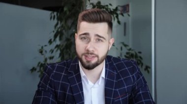 Genç yakışıklı sakallı iş adamı ofiste video görüşmesi sırasında takım elbise giyiyor. İş görüşmesi uygulaması konsepti Webinar. Çevrimiçi seminer. 