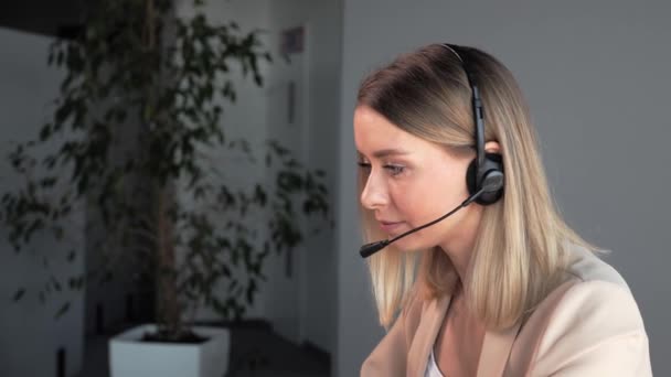 Agent de support client ou centre d'appels avec casque et microphone travaillant sur le lieu de travail tout en soutenant le client sur appel téléphonique. Blonde femme opérateur service entreprise représentatif concept. — Video