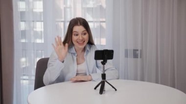 Gülümseyen Kadın video blogu kaydediyor. Dahili ofisteki akıllı telefondan podcast webinar.