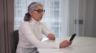 Mutlu kıdemli kadın büyükanne akıllı telefondan kızıyla el sallıyor..