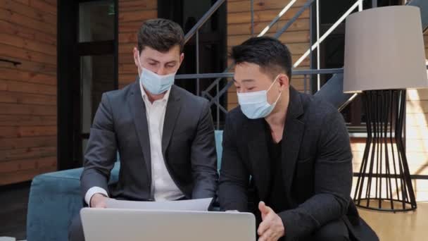 Dos empresarios multinacionales diversos en máscara médica discutiendo asociación. — Vídeo de stock