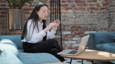 Stresli Çinli iş kadını dizüstü bilgisayarda çalışırken baş ağrısı çekiyor..