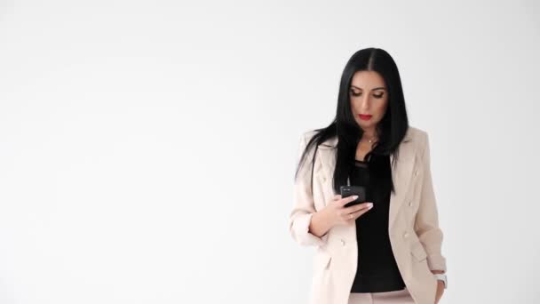 漂亮的女商人拿着手机，在孤独的白色背景上行走. — 图库视频影像