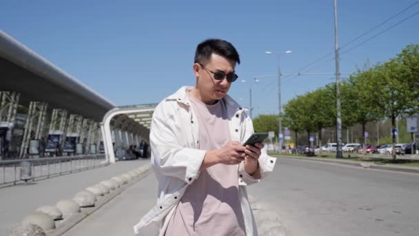 Азиат держит мобильный телефон с помощью приложения для смартфона, чтобы вызвать службу такси. — стоковое видео