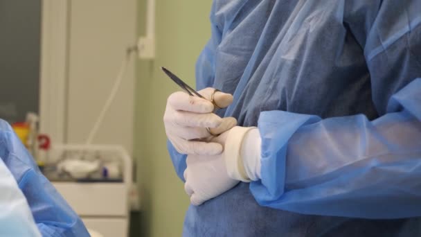 Médico cirujano sostiene tijeras quirúrgicas durante la operación. — Vídeos de Stock