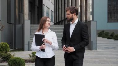 Konsantre iş adamı, iş merkezinin yakınında bayan meslektaşıyla yürüyor..