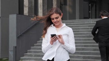 Woman is chatting browsing internet using smartphone colleague hurries to work.