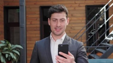 Handsome businessman having video call using his smartphone videoconferencing.