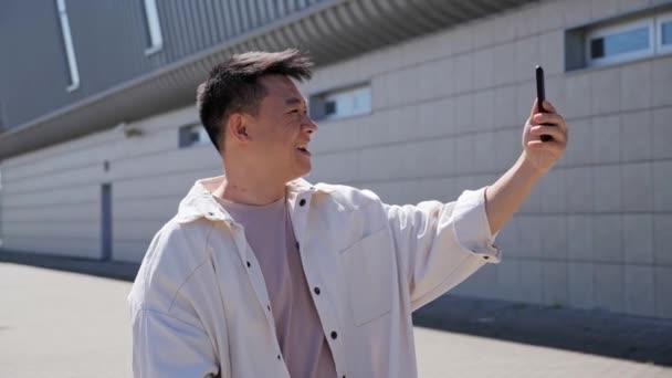 Confident Asian Man Having Video Call with Friend near Modern Building. — Stock Video