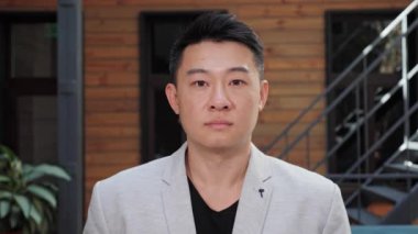 Close up portrait of young confident smart Asian businessman in office room.