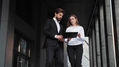 Businessman and businesswoman walking down the stairs in the morning with coffee