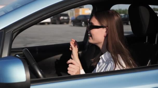 젊은 여성 운전자가 차 안에서 노래부르는 춤을 추는 모습. — 비디오