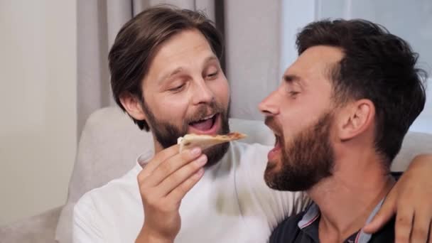 Szczęśliwy mężczyzna homoseksualny gej dokuczanie partner w pokazując a kawałek pizza. — Wideo stockowe