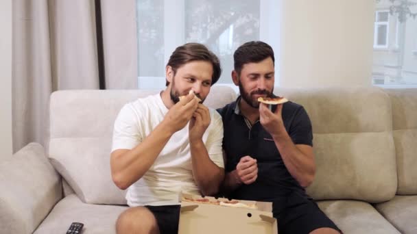 Male same sex couples meeting at home and eating takeaway pizza together. — Stock Video