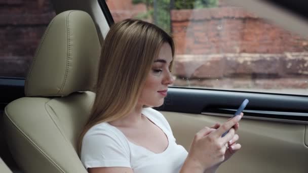 Chica rubia usando la aplicación de teléfono móvil tocando pantalla de desplazamiento en el coche. — Vídeos de Stock