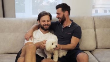 Genç mutlu, homoseksüel bir kadınla evlendi. Kanepede köpeği okşuyor..