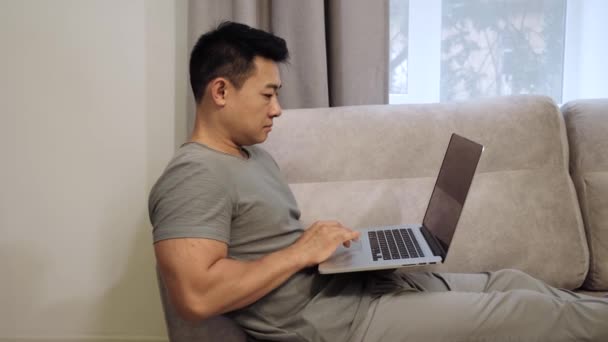 Зосереджений азіатський бізнесмен сидить на Парі, що працює на лаптопі. — стокове відео