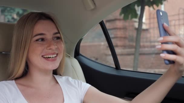 Mujer de negocios sonriente hablando en videollamada por teléfono en automóvil. — Vídeos de Stock