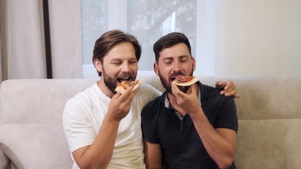 Pasangan pria muda makan pizza di rumah. Kesenangan kaum gay. — Stok Video
