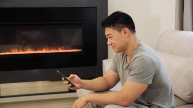 Sosyal medyada kendine güvenen yakışıklı sörfçü koltukta akıllı telefon kullanıyor..