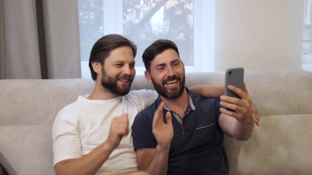 Joven lindo caucásico hombres homosexual pareja usando smartphone haciendo videollamada. — Vídeos de Stock