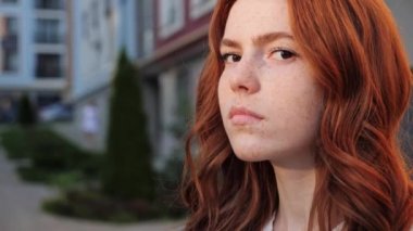 Güzel, genç, kızıl saçlı kadın kameraya ciddi bakmak için başını çeviriyor..