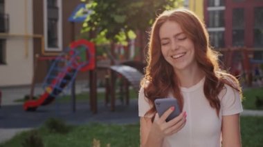  Dışarıda cep telefonunu tutan gülümseyen kadın..