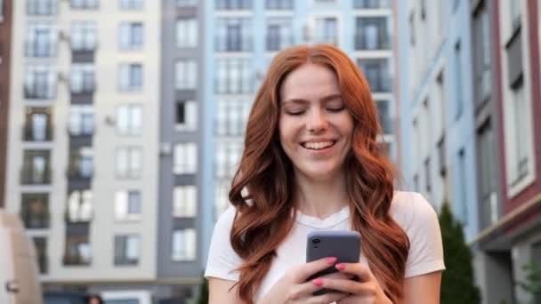 Mujer con pecas escribiendo en el teléfono móvil al aire libre. — Vídeos de Stock