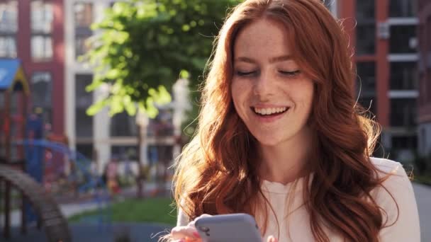 Ingefära dam använder mobiltelefon för att bläddra sociala medier utomhus stadstorget. — Stockvideo