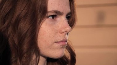 Güzel çilleri olan çekici bir kız. Açık havada poz veriyor. Kahverengi gözleri var..