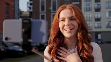 Güzel, mutlu genç kız. Kablosuz tripodu var. Video görüşmesi yapıyor..