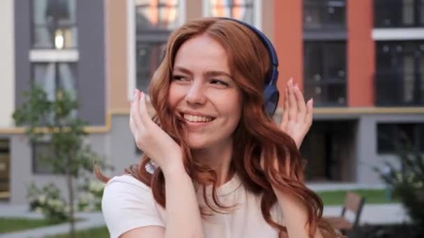 Feliz joven pelirroja mujer disfrutando de la música en la calle. — Vídeos de Stock