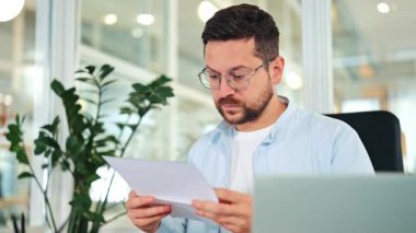 Açık mavi gömlekli, gözlüklü, endişeli işadamı modern ofiste üzücü belgeler okuyor, hayal kırıklığı yaşıyor, stres yaşıyor..