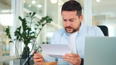 Endişeli iş adamı, açık mavi tişörtlü beyaz tişörtlü, belgeyi parlak modern ofiste okuyor. Hayal kırıklığına uğramış erkek yatırımcı hayal kırıklığı yaşıyor, kötü haberler karşısında şokta ve stresli..
