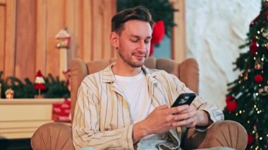 Mutlu yetişkinler Noel boyunca rahat bir evde dinleniyor. Cep telefonuyla konuşurken gülümsemek, festival sezonunun tadını çıkarmak. Mutluluğu, rahatlığı ve modern tatil bağlantısını temsil eder..