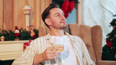 Adam koltukta rahatlıyor, içkinin tadını çıkarıyor. Bayram süslemeleriyle süslenmiş festival odası sıcak atmosfer yaratır. Hoşnutluk anı doldurur, tatil ruhunu mutlu ve huzurlu duygularla doldurur..