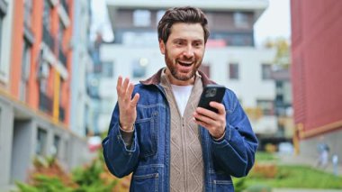 Işınlanan adam inanılmaz bir anın tadını çıkarıyor, akıllı telefondan gelen neşeli haberlere tepki veriyor. Saf zevk ve zaferi ifade eder.